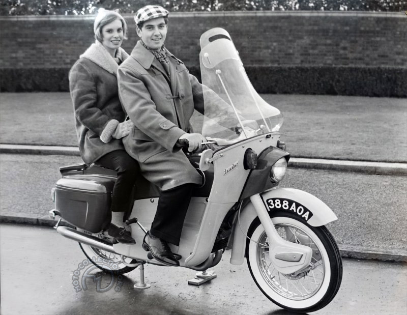 L’ingénieur Bob Trigg passé de la planche à dessin au parking de l’usine pour les photos publicitaires avec mannequin et moto est sur cales !