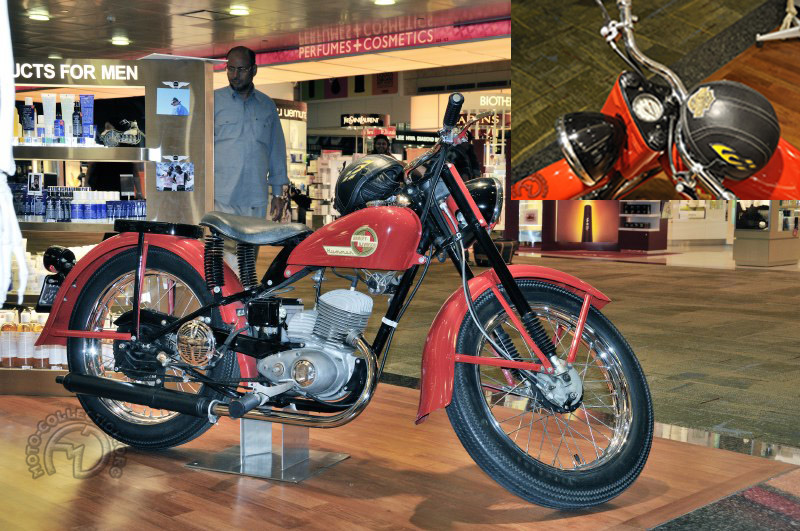 Même petite, l’Harley garde son prestige et cette Hummer 165 cm3 de 1953 reconnaissable à son carbu sous carter était exposée dans une pharmacie de l’aéroport de Singapour. Sous le couvre-chef  de l’heureux pharmacien se cachent deux bouchons, pour l’essence et pour le réservoir d’huile intégré. 